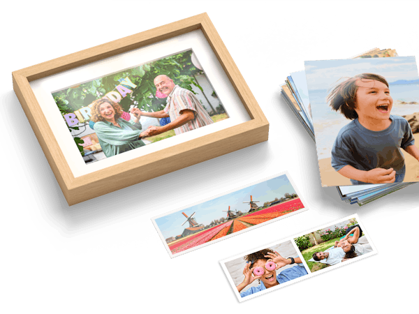 Een stapel fotoafdrukken, fotostrips en een foto in een lijst met zomerse familiefoto's