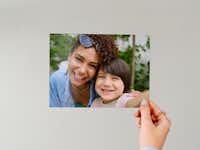 Fotoafdruk 15 cm Hand die een fotoafdruk van 15 cm met daarop een familie vasthoudt voor een neutrale achtergrond