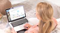 Online-Designer auf der Website Frau mit einem Laptop, auf dem der Online-Designer für das Pixum Fotobuch gezeigt wird