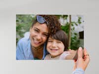 Fotoafdruk 20 cm Hand die een fotoafdruk van 20 cm met daarop een familie vasthoudt voor een neutrale achtergrond